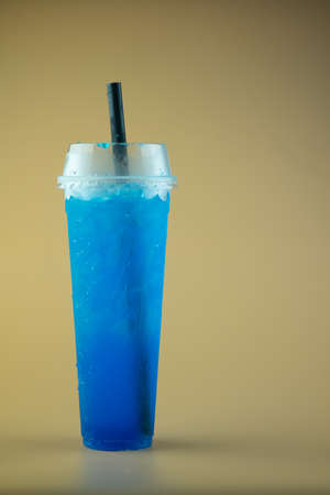 Iced blue lime soda in tall plastic glass with black strawの写真素材