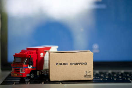 Online shopping of brown parcel box and model miniature postal car. Concept of parcelの写真素材