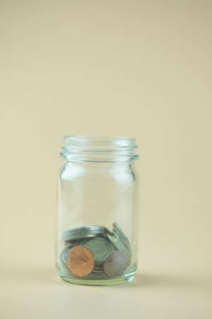 Close up of Thai coins in glass jar. Saving money concept with copy space.