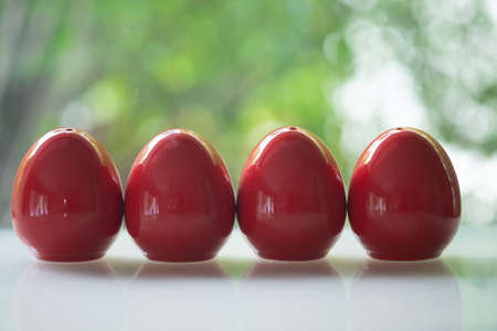 Four red of egg shape ceramic shakers for salt and pepper on table
