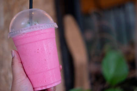 Healthy strawberry yogurt smoothie in plastic glass in handの写真素材