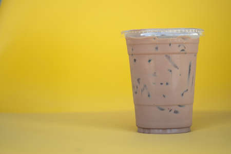Cold Mocha coffee drink in takeaway glass on yellow background