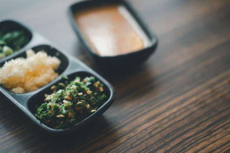 Set of slice vegetable, garlic, chill and chives on black tray for topping sauce in shabu style