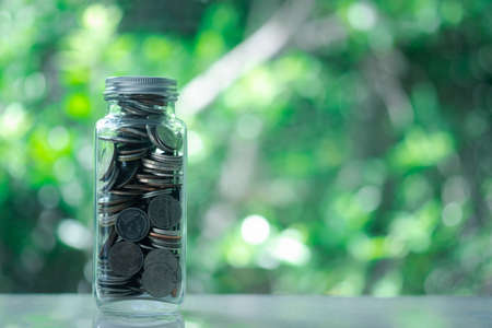 Thai coins in glass jar  on blur nature background with copy space. Saving money concept.の写真素材