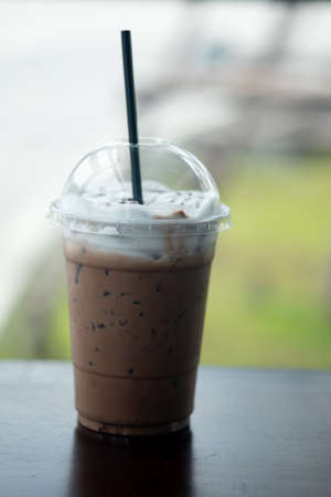 Iced mocha coffee with milk cream on top in plastic glassの写真素材