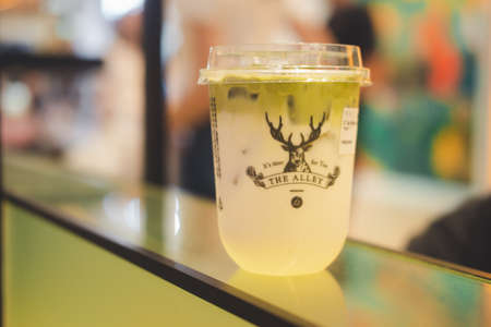 Samut Prakan, Thailand - August 2, 2020 : A plastic glass of iced milk green tea at The Alley Store. Close up.のeditorial素材