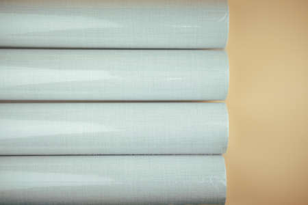Wallpaper for decorating walls and repairs twisted into rolls in plastic packaging on orange...
