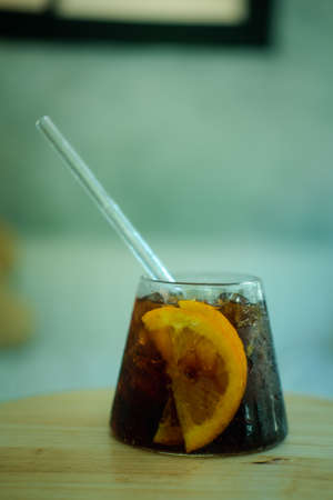 Cool soft drink with orange slices inside glass on wooden table