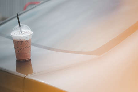 Old man forget iced Mocha coffee in plastic glass on front roof of car.の写真素材
