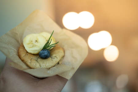 Delicious banana cupcake topping with sliced banana and blueberry in handの写真素材