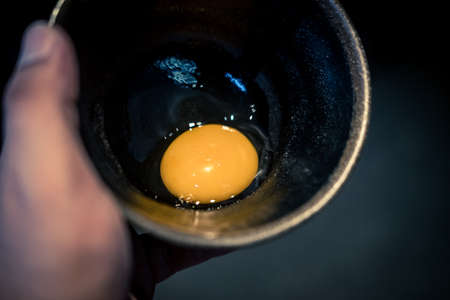 Close-up raw uncooked egg in black bowl. Ingredient for cooking