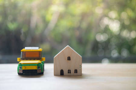 Toy car with miniature house against on wood table blur nature backgroundの写真素材
