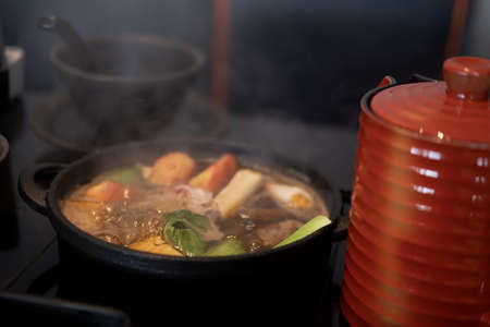 Japanese Sukiyaki pork, beef and mix vegetable boiled in black soup in traditional cast iron pot. Selective focusの写真素材