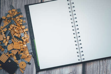 Golden plastic blocks with empty paper notebook on wood tableの写真素材