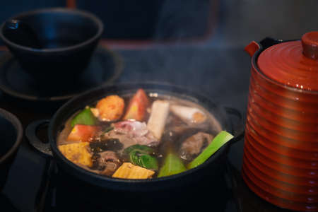 Japanese Sukiyaki pork, beef and mix vegetable boiled in black soup in traditional cast iron pot. Selective focusの写真素材