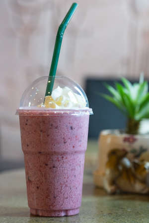 Blueberry smoothie yoghurt with whipped cream in plastic glass