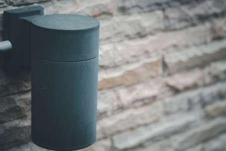 Black metal classic lamp with light bulb hanging on brick wall in gardenの写真素材