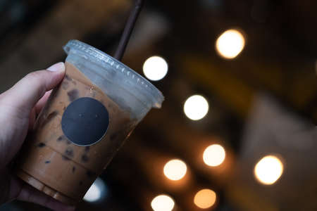 Hand hold iced mocha on light blur background. Refreshing drinkの写真素材