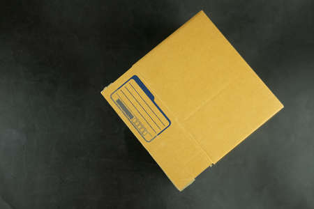 Close up of small packet of brown box with empty for write address sender on a black background