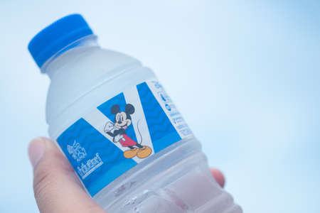 Bangkok, Thailand - November 8, 2020 : Singha drinking water Mickey Mouse Collection size 330 ml. in hand on the skyのeditorial素材