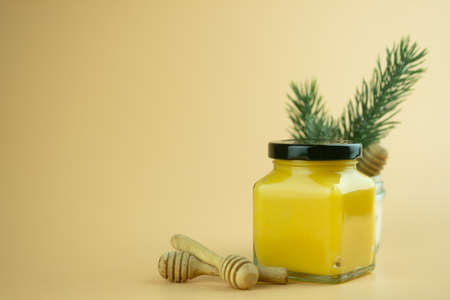 Homemade lemon curd in small glass jar with black lid on yellow background, copy spaceの写真素材