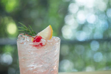 Pink cocktail with lychee syrup and sparkling soda decoration with rosemary cherries and slice lemon. Concept of homemade refreshmentの写真素材