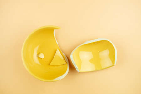 Broken ceramic yellow bowl on a yellow backgroundの写真素材
