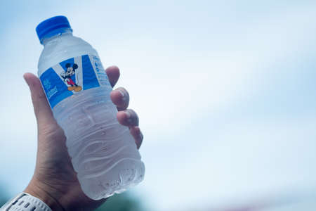 Bangkok, Thailand - November 15, 2020 : Singha drinking water Mickey Mouse Collection size 330 ml. in hand on the skyのeditorial素材