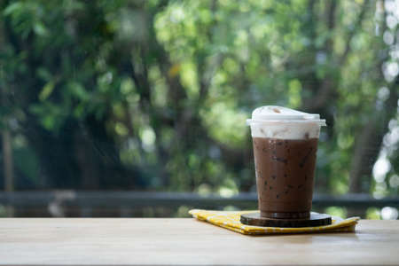 Iced mocha in plastic cup on wooden table. Coffee beverage in coffee houseの写真素材