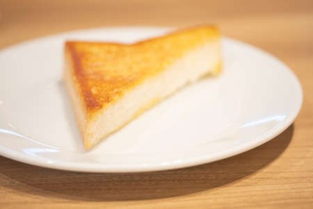 Triangle of garlic bread on white dish. Selective focus