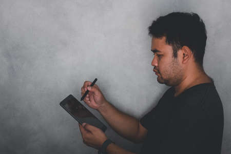 Handsome big moustache hipster man using tablet on gray backgroundの写真素材