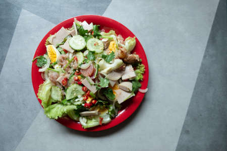 Spicy pork salad with mixed vegetable on red plate. Thai style homemade foodの写真素材