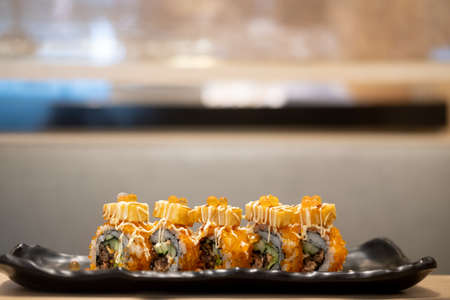 Maki sushi salmon roe on top with tamako served on black tray.の写真素材
