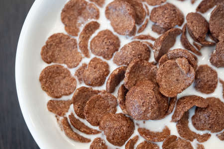 Breakfast cereal chocolate cornflakes with fresh milk in white bowl. Eating healthy breakfast