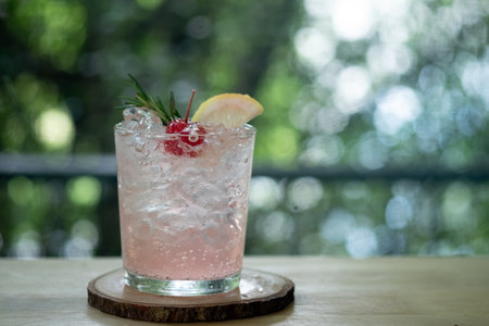 Pink cocktail with lychee syrup and sparkling soda decoration with rosemary cherries and slice...