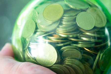 Money coins Thai baht in a green round glass jar on handの写真素材