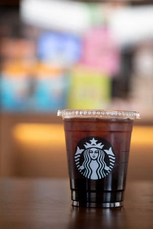 Bangkok, Thailand - December 13, 2020 : Iced americano in take-away cup on wood table at Starbucks cafe coffee shopのeditorial素材