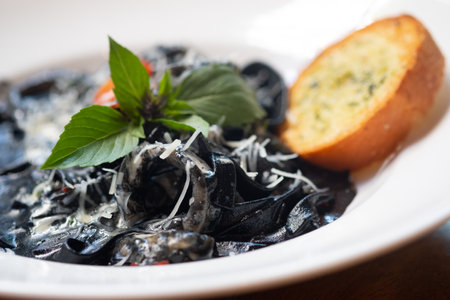 Italian black spaghetti pasta with squid rings served with garlic breadの写真素材