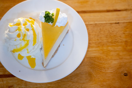 A slice of lemon cheesecake with thin chocolate biscuit served with whipped cream.の写真素材