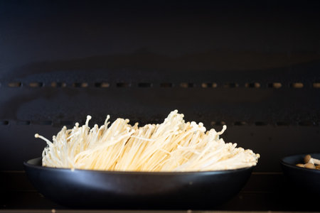 Raw Enoki Mushrooms for chinese hot pot on black dish