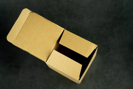 Empty open cardboard box on black background, top view