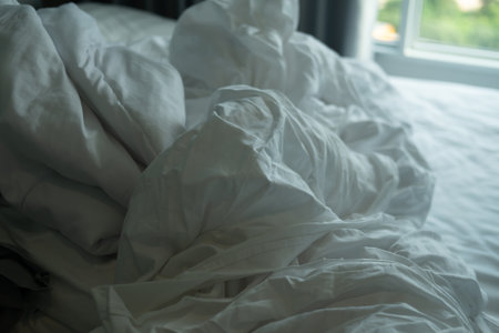 Morning view of an unmade bed with crumpled white bed linensの写真素材