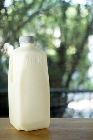Big white plastic fresh milk bottle with gray cap on wood table. Breakfast drink for health.の写真素材