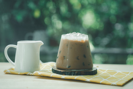 A cup of iced Mocha coffee with fresh milk in jar on wood table in gardenの写真素材