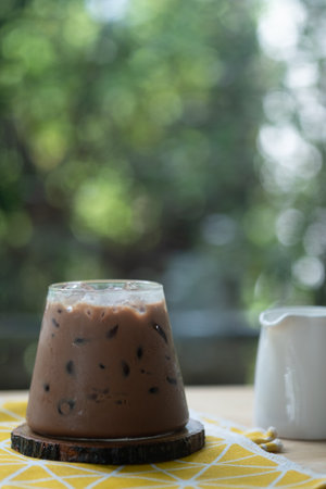 A cup of iced Mocha coffee with fresh milk in jar on wood table in gardenの写真素材