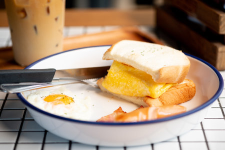 Egg in sandwich, sausage and bacon served with iced coffee. Morning healthy breakfast