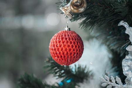 Closeup of red ball hanging from a decorated Christmas treeの写真素材