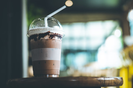 Ice cold coffee mocha in plastic glass on wood table at coffee shop. Refreshing drink