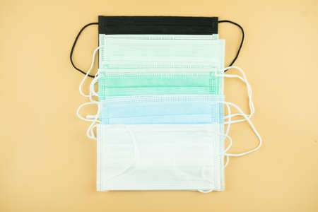 Many of colored medical masks on yellow colored background to cover the mouth and nose for...