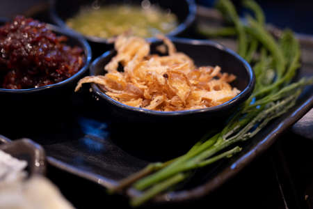 Selective focus of side dish fried onion, chili paste, acacia shoots and Thai spicy and sour sauce for eating raw fresh oyster recipe. Thai seafood style conceptの写真素材